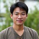 Portrait of David Chen, a knowledgeable man with a thoughtful expression, perhaps in a greenhouse.